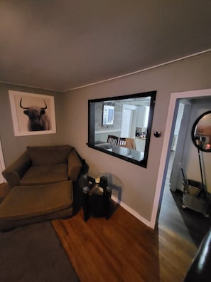 A living room with a sofa, a mounted TV, a bull head decoration, and a door leading to another room.