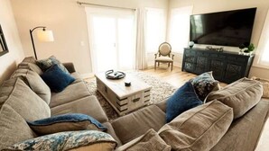 A living room with a sofa, a coffee table, a TV, and a cabinet. - Three Seas 2, steps from the beach (Carolina Beach)