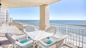 A balcony with white wicker furniture and a view of the ocean.