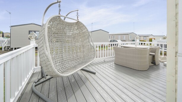 A wooden deck with a white wicker chair and a wicker sofa. - 3 Bedroom Mersea Beach Retreat-getaway by the Sea (Colchester)
