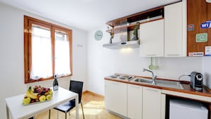 A compact kitchen with a dining table, a sink, and a refrigerator.