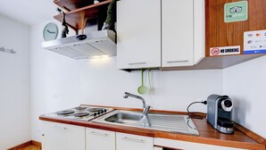 A kitchenette with a stove, sink, and coffee maker.