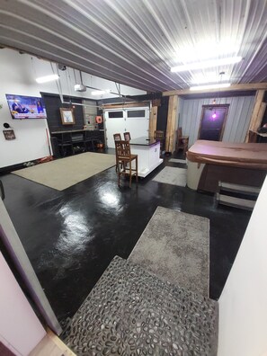 A spacious room with a black and white color scheme, a kitchen area, and a seating area with chairs and a table. - Cozy studio with  indoor hot tub (South Wales)