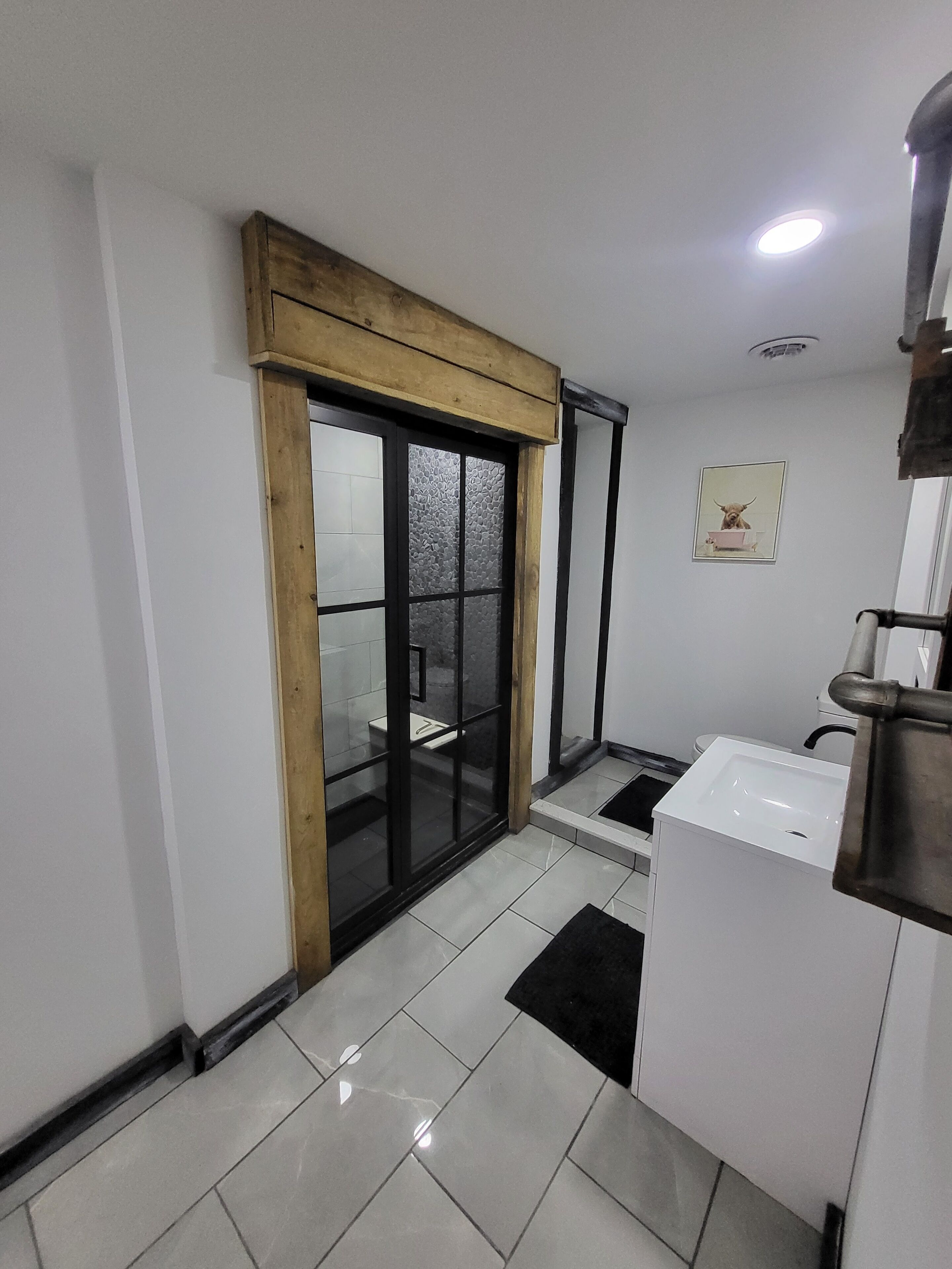 A modern bathroom with a white sink, a mirror, and a framed picture on the wall.. Cozy studio with  indoor hot tub