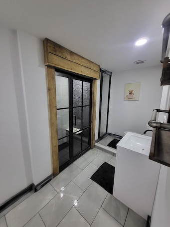 A modern bathroom with a white sink, a mirror, and a framed picture on the wall.. Cozy studio with indoor hot tub
