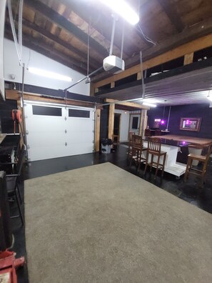 Eine Garage mit weißer Tür, Werkbank und Tisch mit Stühlen.