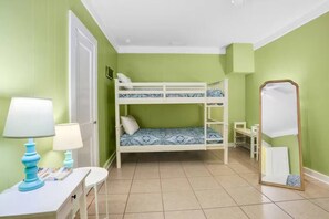Une chambre avec un lit superposé, un bureau avec une lampe, une chaise et un miroir.