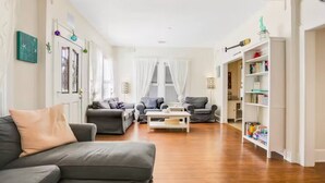 A living room with a grey sofa, a coffee table, and a bookshelf filled with books. - Spacious Home with Bikes, Near Historic Downtown (St. Augustine)