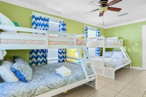 Een kamer met stapelbedden, een plafondventilator en gordijnen met een zigzaggemotief.