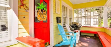 A porch with a red door, a ceiling fan, and a wooden deck.