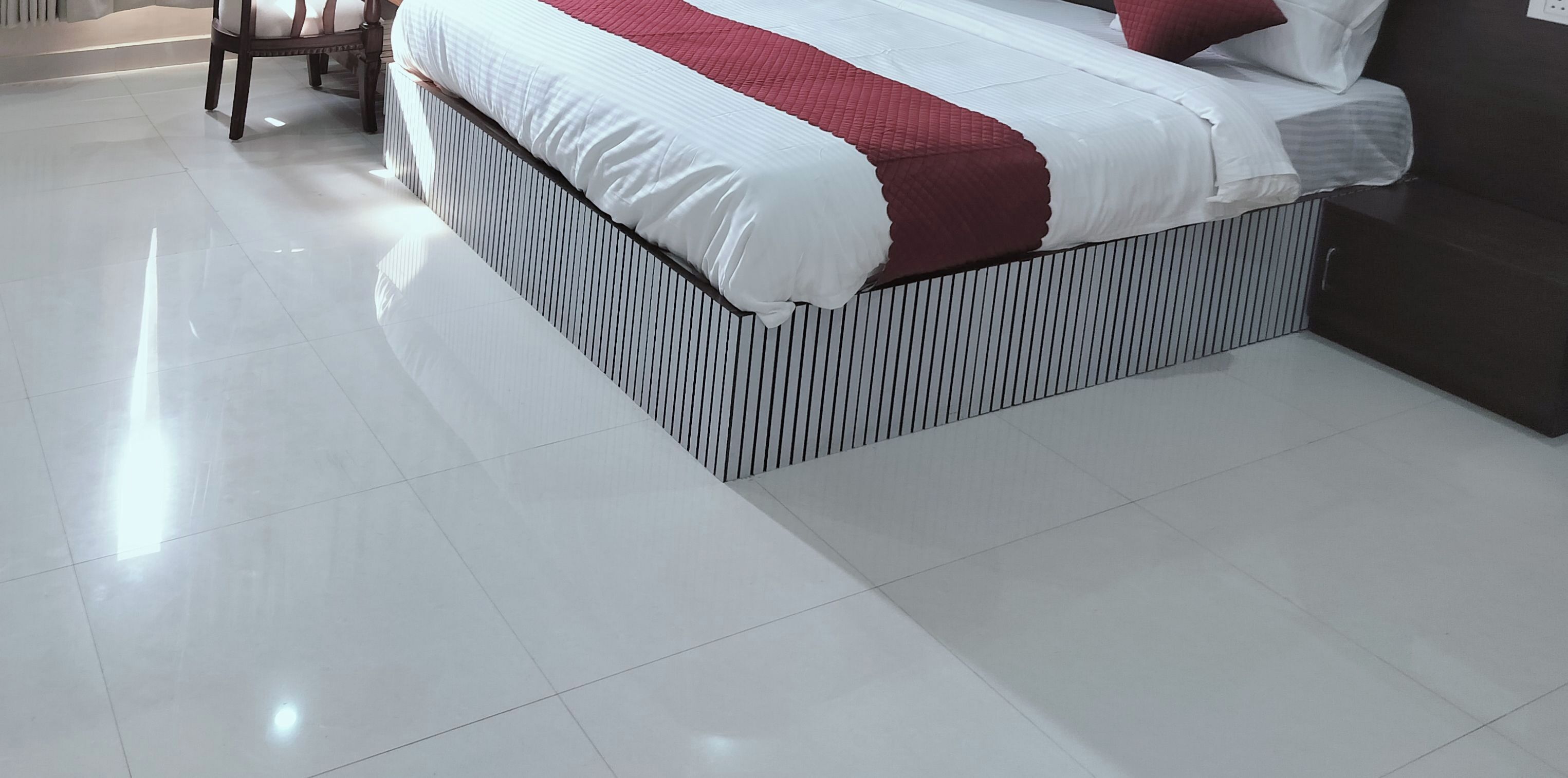 A modern hotel room with a large bed, a chair, and a dark-colored sofa.