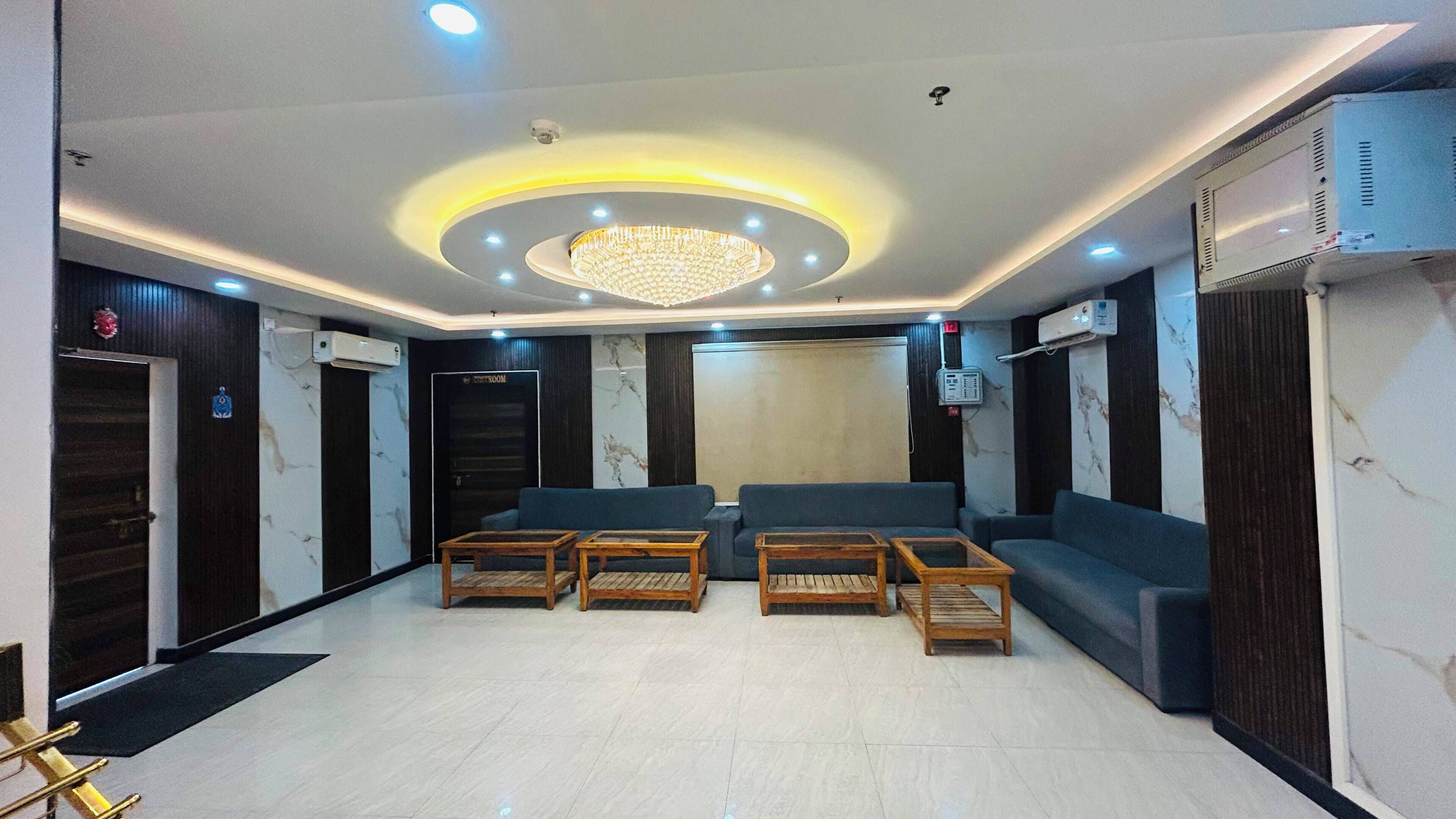 Un hall con candelabro, sofás y mostrador de recepción.