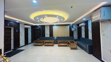 A lobby with a chandelier, sofas, and a reception desk.