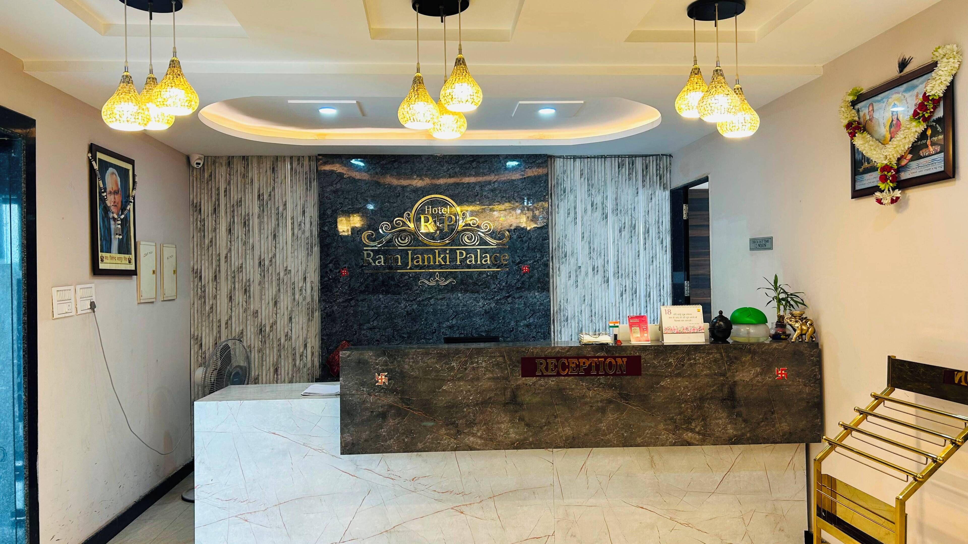 A hotel reception desk with a marble top, a framed sign above it, and a reception area with a curtain and a wall-mounted fan.
