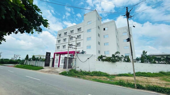 A multi-story building with a gated entrance, a covered area, and a flat-roofed structure. - Hotel Ram Janki Palace (Pindra)