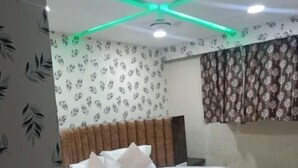 A bedroom with a round bed, a headboard, and a ceiling light fixture. - Hotel Raj Palace (Ahmedabad)