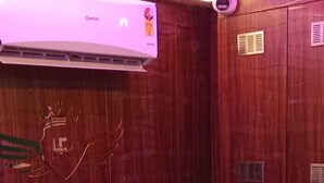 A reception area with a curved reception desk, a white towel draped over the desk, and a wooden wall with a coat of arms. - Hotel Raj Palace (Ahmedabad)