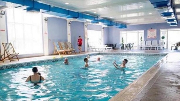 An indoor swimming pool with clear blue water, tiled walls, and a blue ceiling. - Seafront Cozy Static Caravan With Sea Vievs (Aberystwyth)