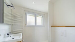 Une salle de bain avec un lavabo blanc, un miroir et une fenêtre.