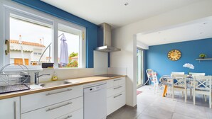 A modern kitchen with white cabinets, a stainless steel sink, and a window overlooking a residential area. - House with garden, beach 15 min walk - 6 guests (Les Sables-d´Olonne)
