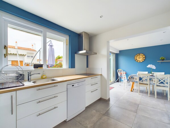 A modern kitchen with white cabinets, a stainless steel sink, and a window overlooking a residential area.