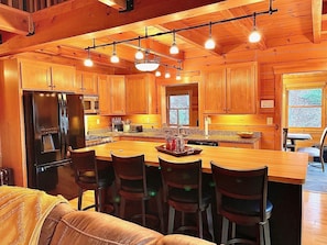 A wooden cabin interior with a kitchen, dining area, and a cozy living space.