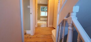 A wooden staircase leading to a room with a window, a door, and a woven mat on the floor. - Cosy & Stylish Stay in Vibrant East Ham (Greater London)
