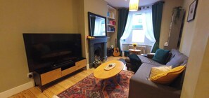 Een woonkamer met een flatscreen televisie, een open haard, een bank en een salontafel.
