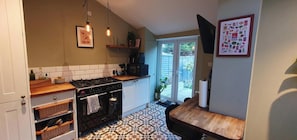 A kitchen with a stove, oven, and tiled backsplash. - Cosy & Stylish Stay in Vibrant East Ham (Greater London)