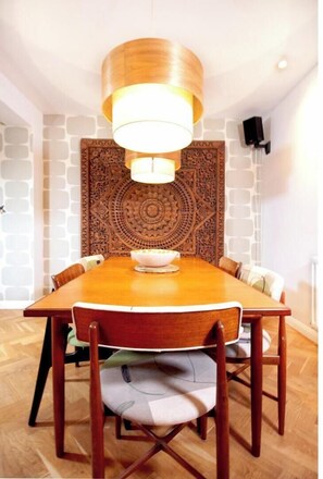 Enjoy meals in this dining area with a wooden table and chairs, a pendant light, and a decorative wall panel.