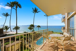 Ein Balkon mit Pool, Palmen und Blick auf den Ozean.