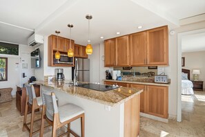Eine moderne Küche mit Granit Arbeitsplatten, Holzschränken und einer zentralen Kochinsel mit Barhocker.