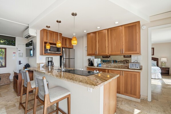A modern kitchen with granite countertops, wooden cabinets, and a central island with bar stools.