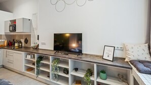 Une cuisine moderne dotée d’un téléviseur encastré, de meubles blancs et d’une œuvre d’art décorative au mur.