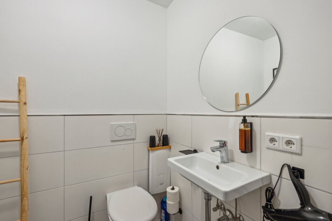 Ein Badezimmer mit weißem Waschbecken, Spiegel, Toilette und Handtuchhalter.
