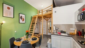 Une cuisine compacte équipée d’un micro-ondes encastré, d’un petit évier et d’un escalier en bois menant à un niveau supérieur.