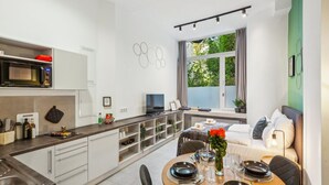 Une cuisine moderne avec un coin repas, des meubles blancs et une vue sur la verdure environnante.