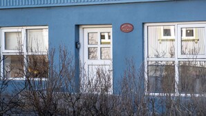 Um edifício com fachada azul, várias janelas e uma placa indicando ser um 'Mariubær Apartment'.