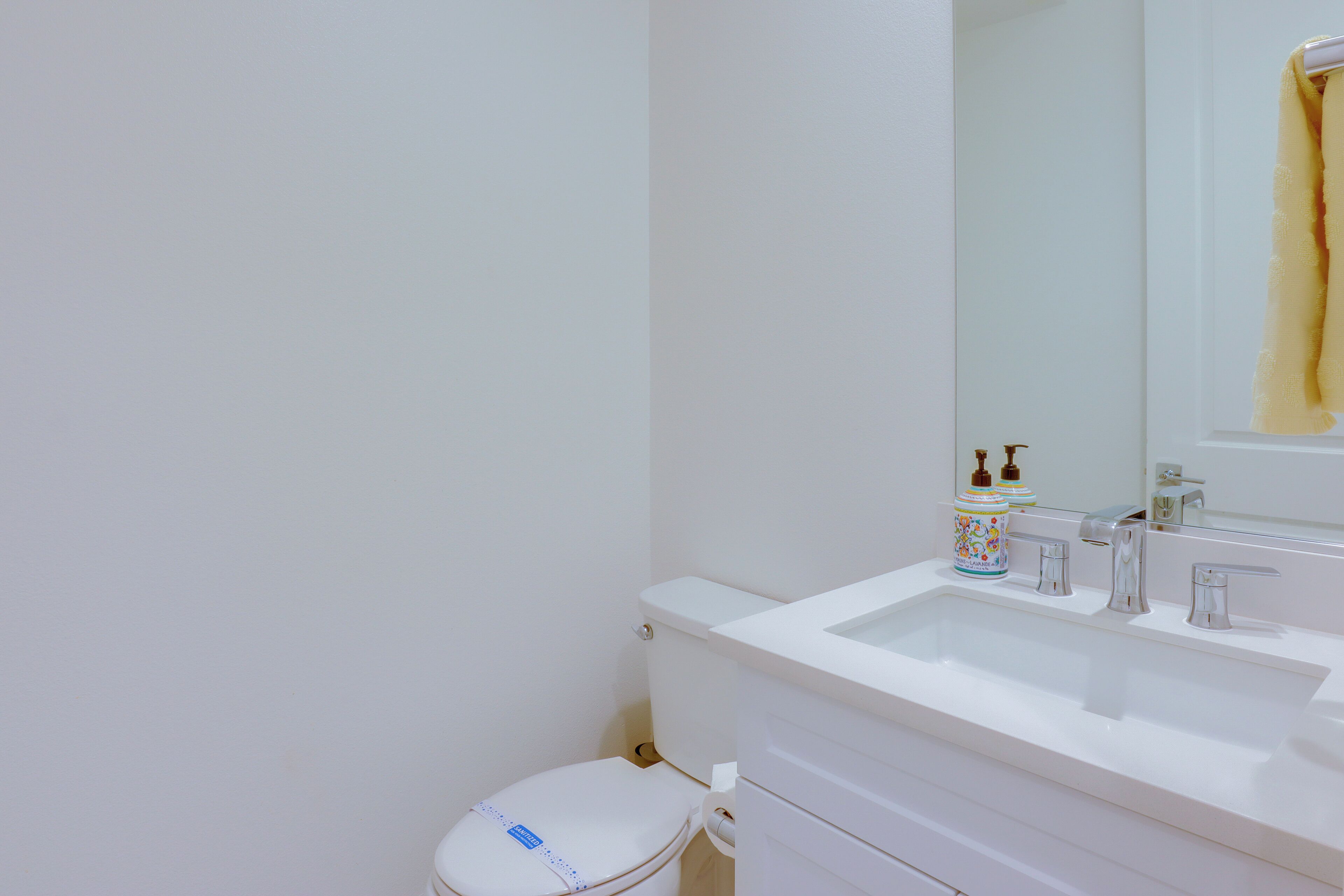 Une salle de bain avec un lavabo blanc, des toilettes et un miroir.