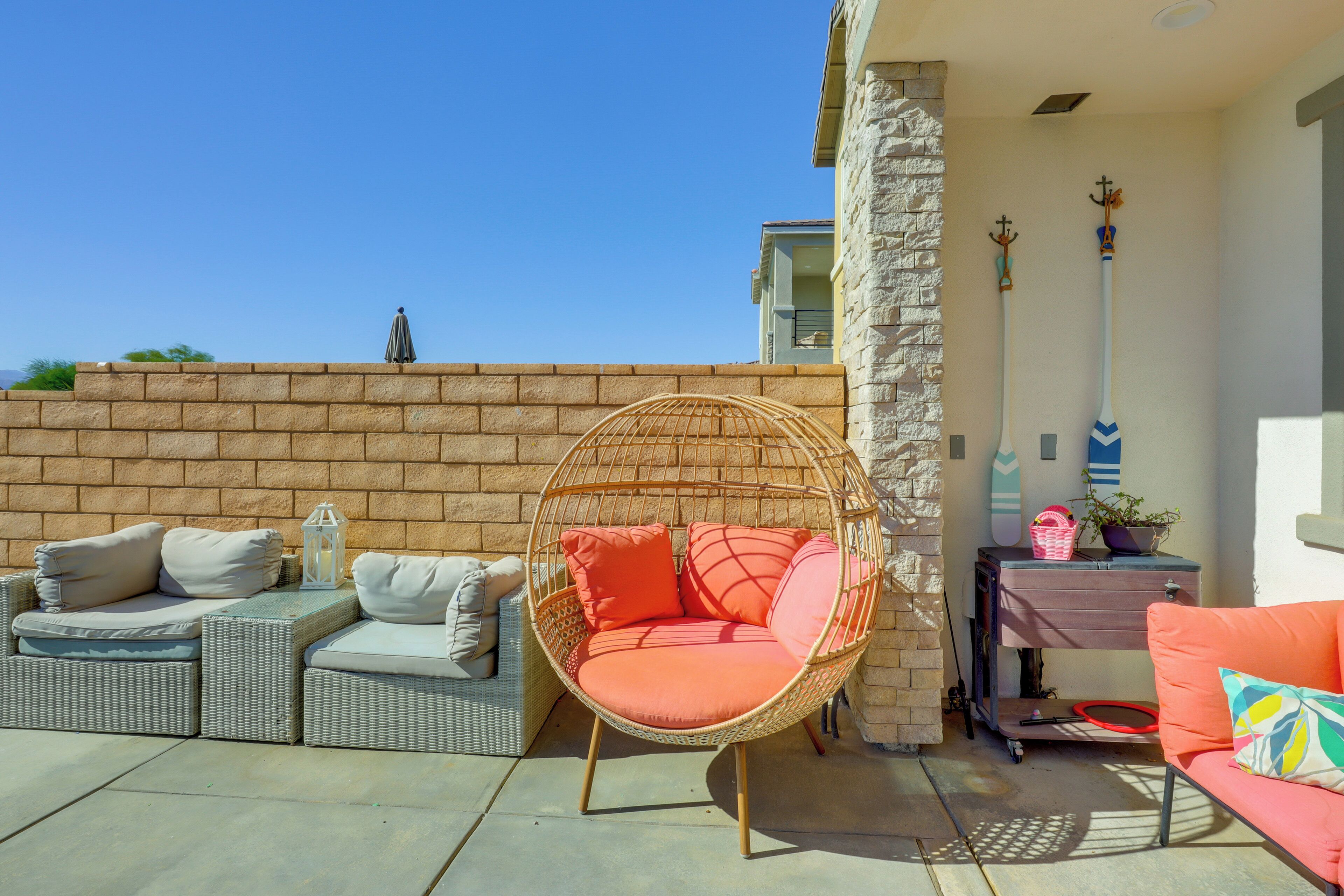 A patio area with wicker furniture, a hanging chair, and a small table with decorative items.