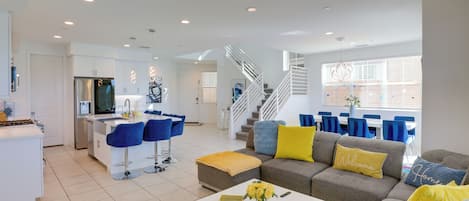 A modern living space with a kitchen, dining area, and a staircase leading to an upper level.