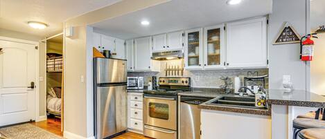 A modern kitchen with stainless steel appliances, white cabinets, and a wooden floor.