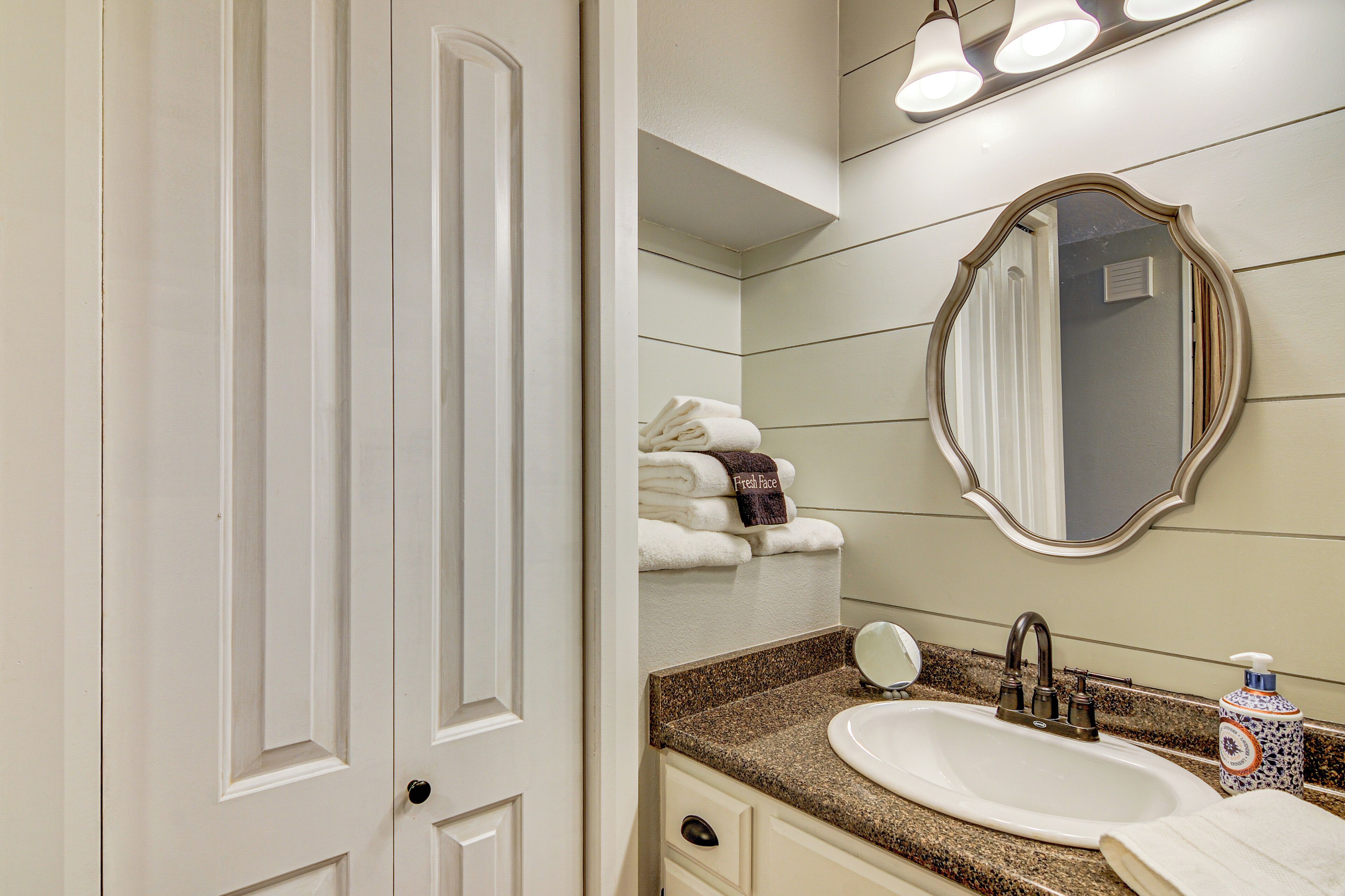 A bathroom with a white sink, a mirror, and a towel rack with folded towels.