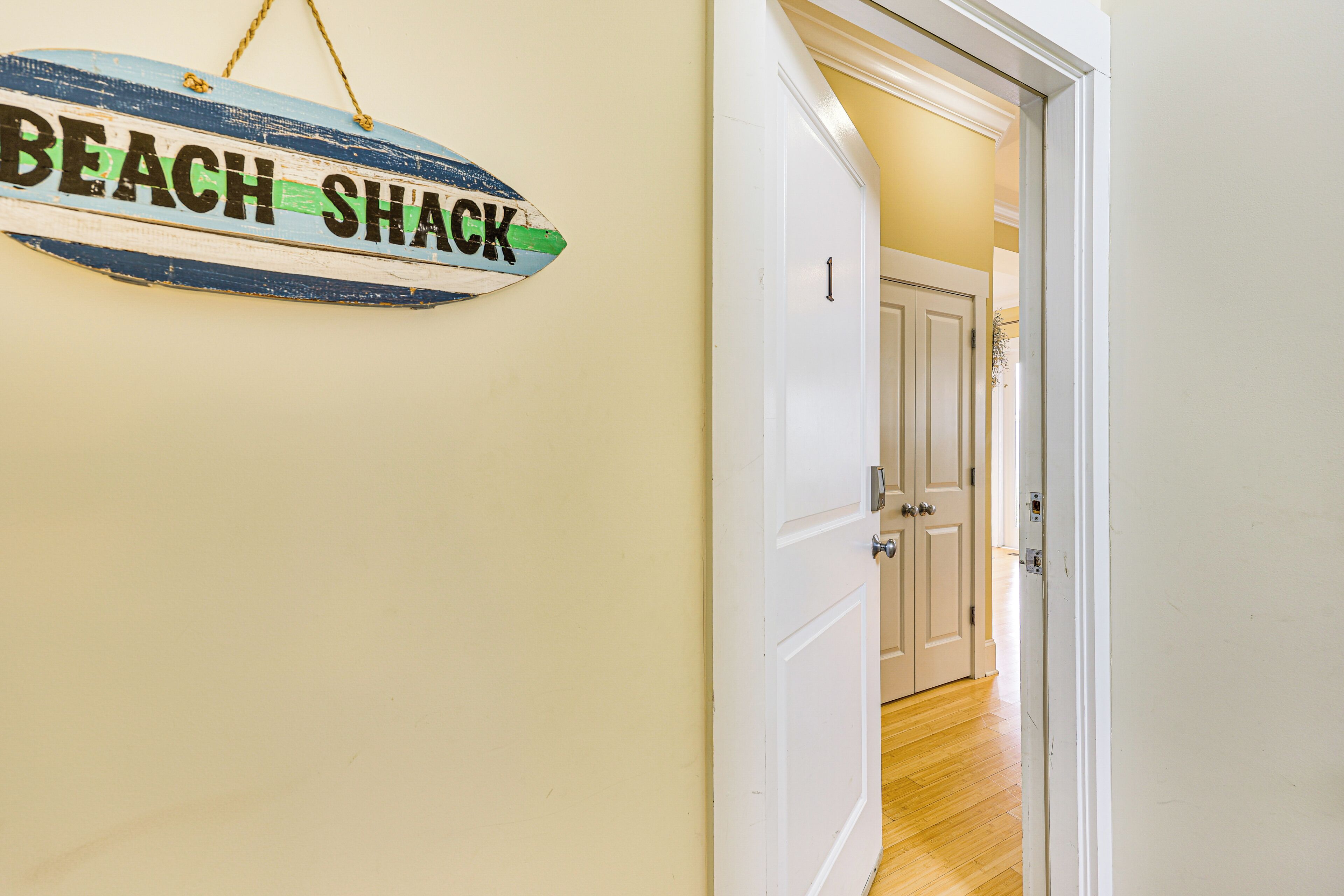 A hallway with a door labeled "BEACH SHACK" and a white door with a number "1" on it.