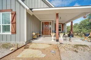 A house with a covered porch, a front door, and a small garden area with a pathway leading to the door. - 'rustic Retreat - Scenic Hill Country Escape (Johnson City)