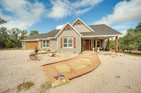 A two-story house with a covered porch, a garage, and a gravel driveway. - 'rustic Retreat - Scenic Hill Country Escape (Johnson City)