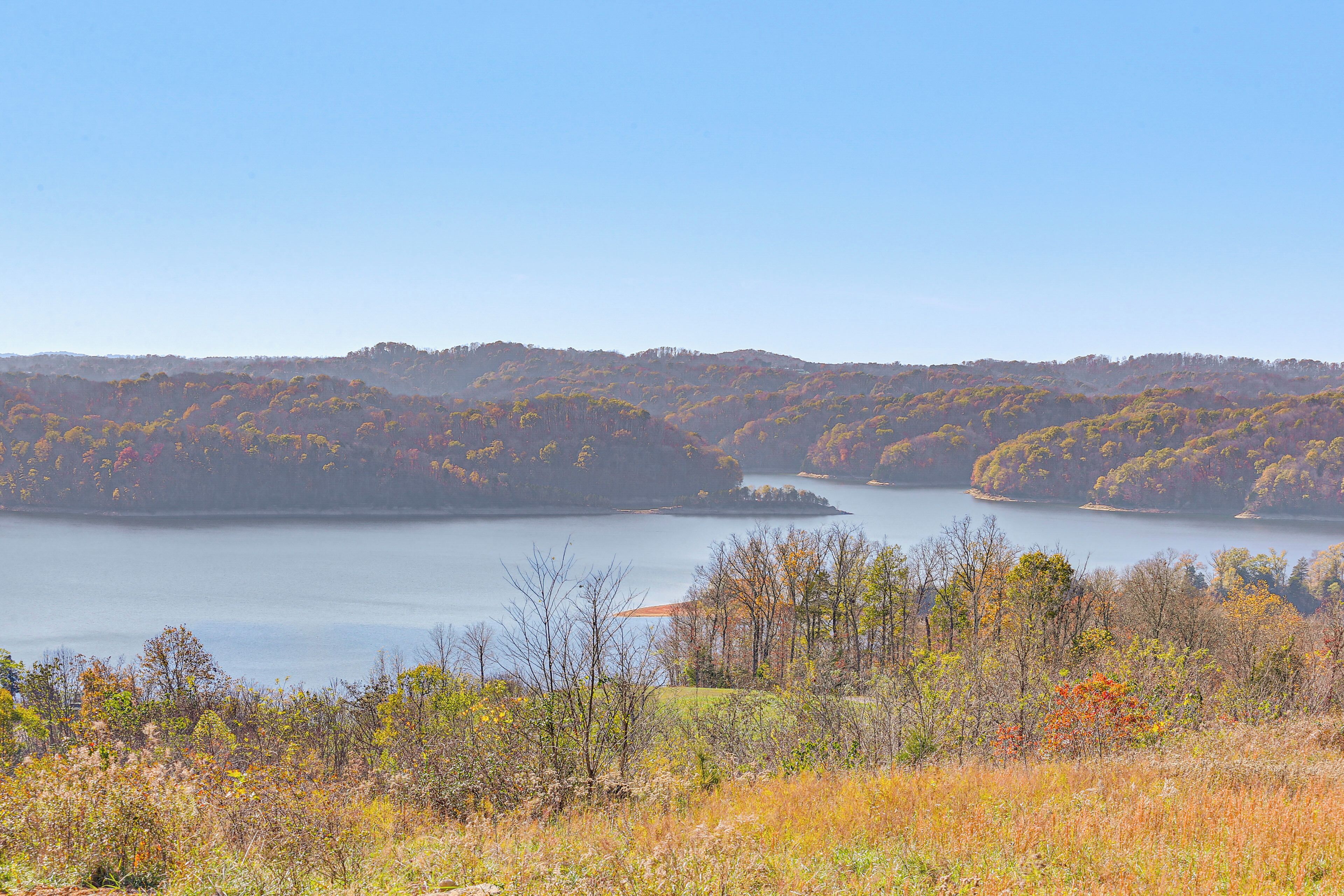 A view of a lake surrounded by hills with autumn foliage.