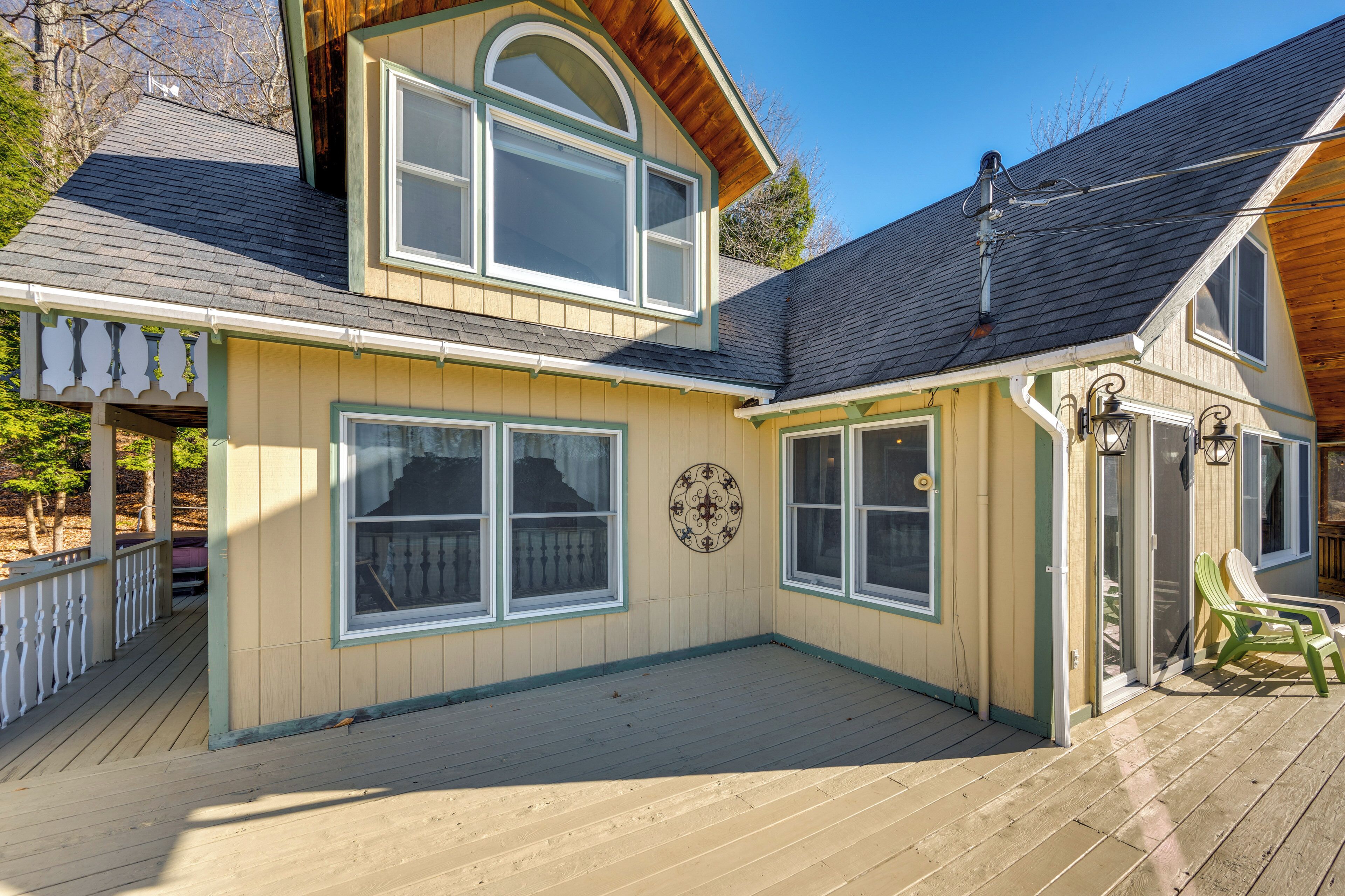 A two-story house with a covered deck, large windows, and a decorative wall plate.