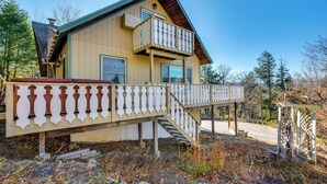 Una casa a due piani con un balcone e una scala in legno che conduce all'ingresso.