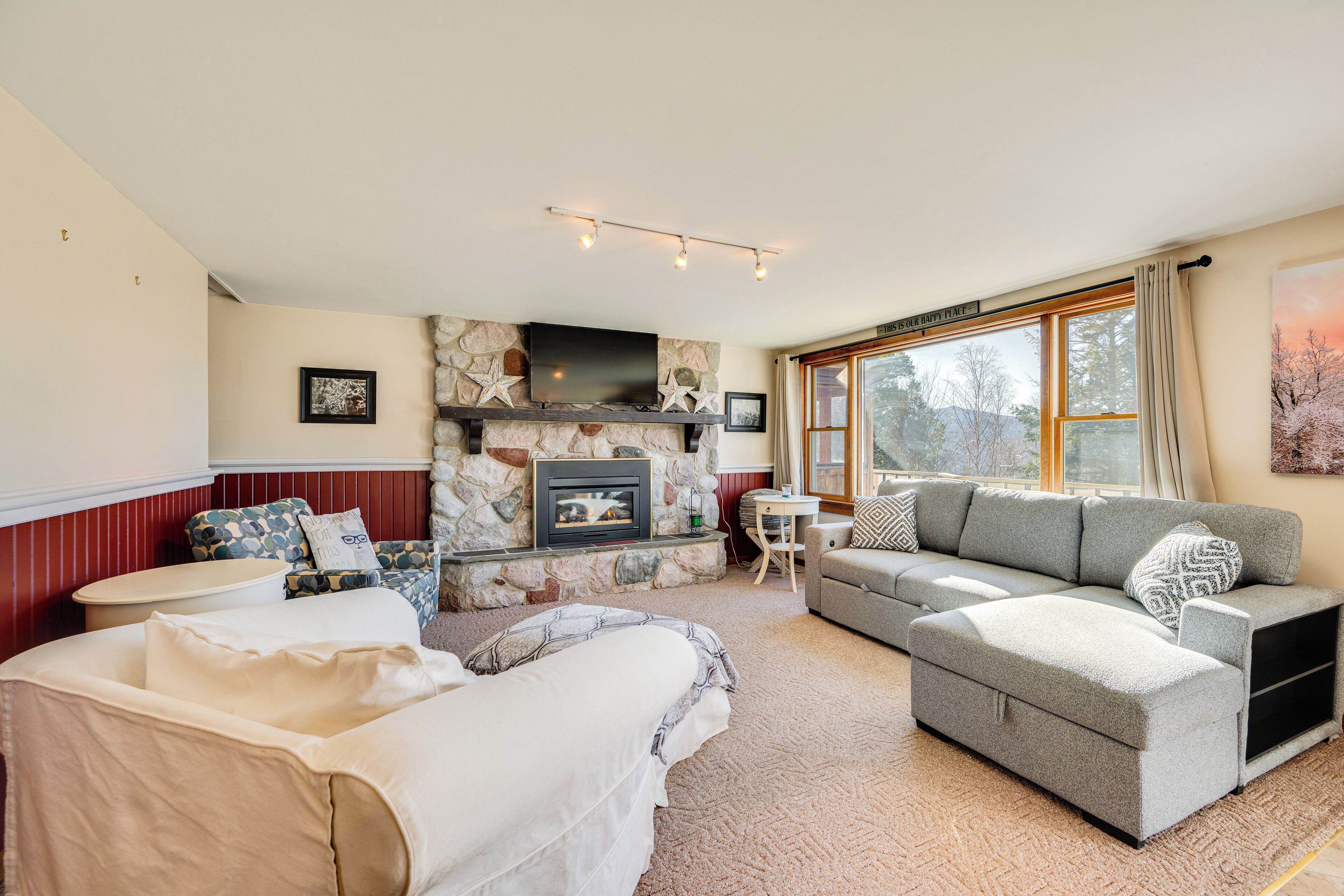 A cozy living room with a stone fireplace, a sofa, a loveseat, and a coffee table.